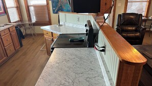 Una cocina con encimera de mármol, armarios de madera y una silla negra.