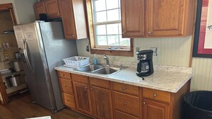 Una cocina con armarios de madera, un refrigerador de acero inoxidable, un lavamanos doble y una cafetera.