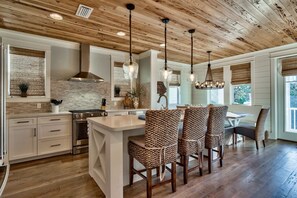 Una cocina moderna con una isla central, techo de madera e iluminación colgante.
