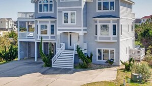 A two-story house with a front porch, a staircase, and a garage. - Oceanview Dog Friendly Home w/ Pool, Hot Tub, Elevator, Game and Media Rooms (Avon)