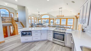 A spacious kitchen with a large island, built-in appliances, and a view of the outside. - Oceanview Dog Friendly Home w/ Pool, Hot Tub, Elevator, Game and Media Rooms (Avon)
