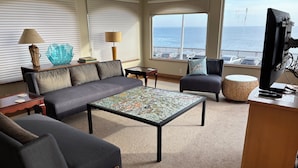 Una sala de estar con sofá, sillón, mesa de centro y televisor.