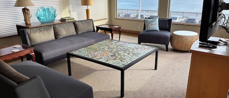 A living room with a sofa, armchair, coffee table, and a television.