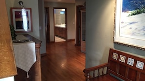 Un pasillo amplio con suelo de madera, un comedor con mesa y sillas de madera, y una cocina visible a través de una puerta abierta.