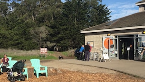 Un edificio con un letrero, mesas al aire libre y un perro.