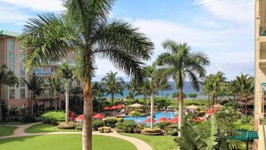 Um resort com piscina, palmeiras e vista para o oceano.