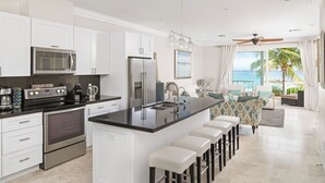 Una cocina moderna con armarios blancos, electrodomésticos de acero inoxidable y una isla central con taburetes de bar.