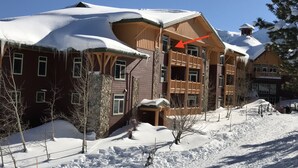 A multi-story wooden building with a snow-covered roof, surrounded by snow.