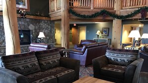 A cozy lobby with leather sofas, a stone fireplace, and a wooden ceiling.