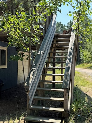 Staircase leads to a simple, rustic structure surrounded by lush greenery.