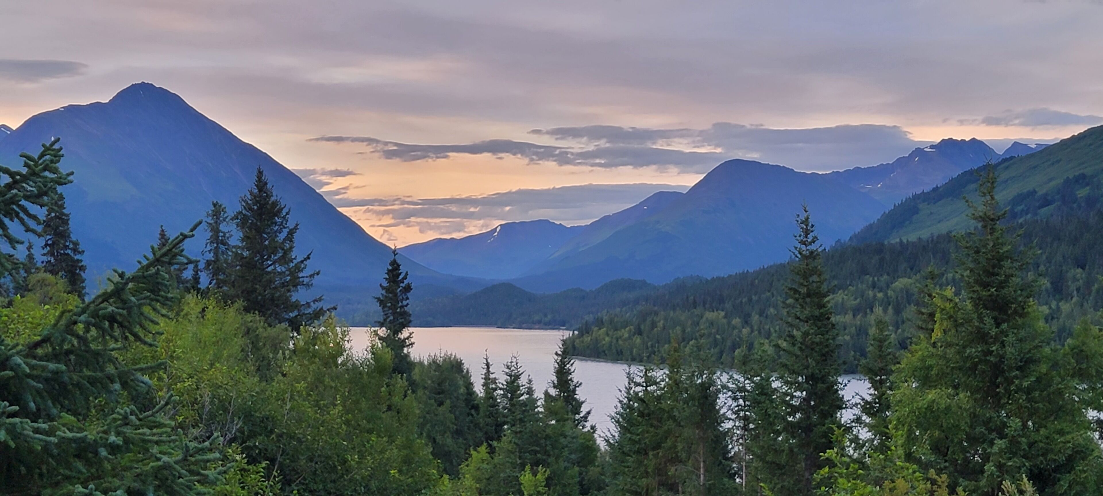 A mountainous landscape with a lake and dense forest.