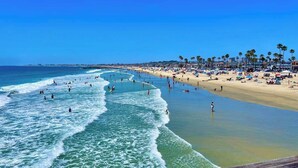 Ein Strand mit Menschen, Palmen und blauem Himmel.