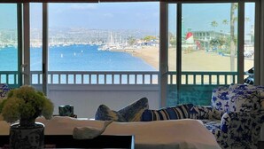 Ein Zimmer mit Meer- und Strandblick, ausgestattet mit einer Couch, einer Vase mit Blumen und einem Tisch mit einem dekorativen Gegenstand.