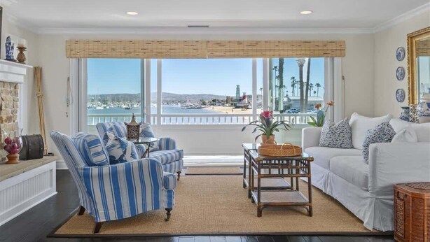 Ein Wohnzimmer mit Blick auf den Hafen, ein weißes Sofa, ein gestreifter Sessel und ein kleiner Tisch.