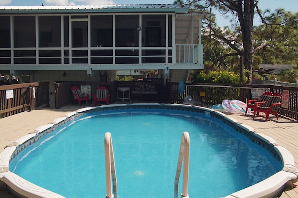 Ridiculously relaxing screened in porch overlooks large pool and huge pool deck.