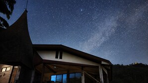 Una casa con un balcón grande, un telescopio y vistas del cielo nocturno.
