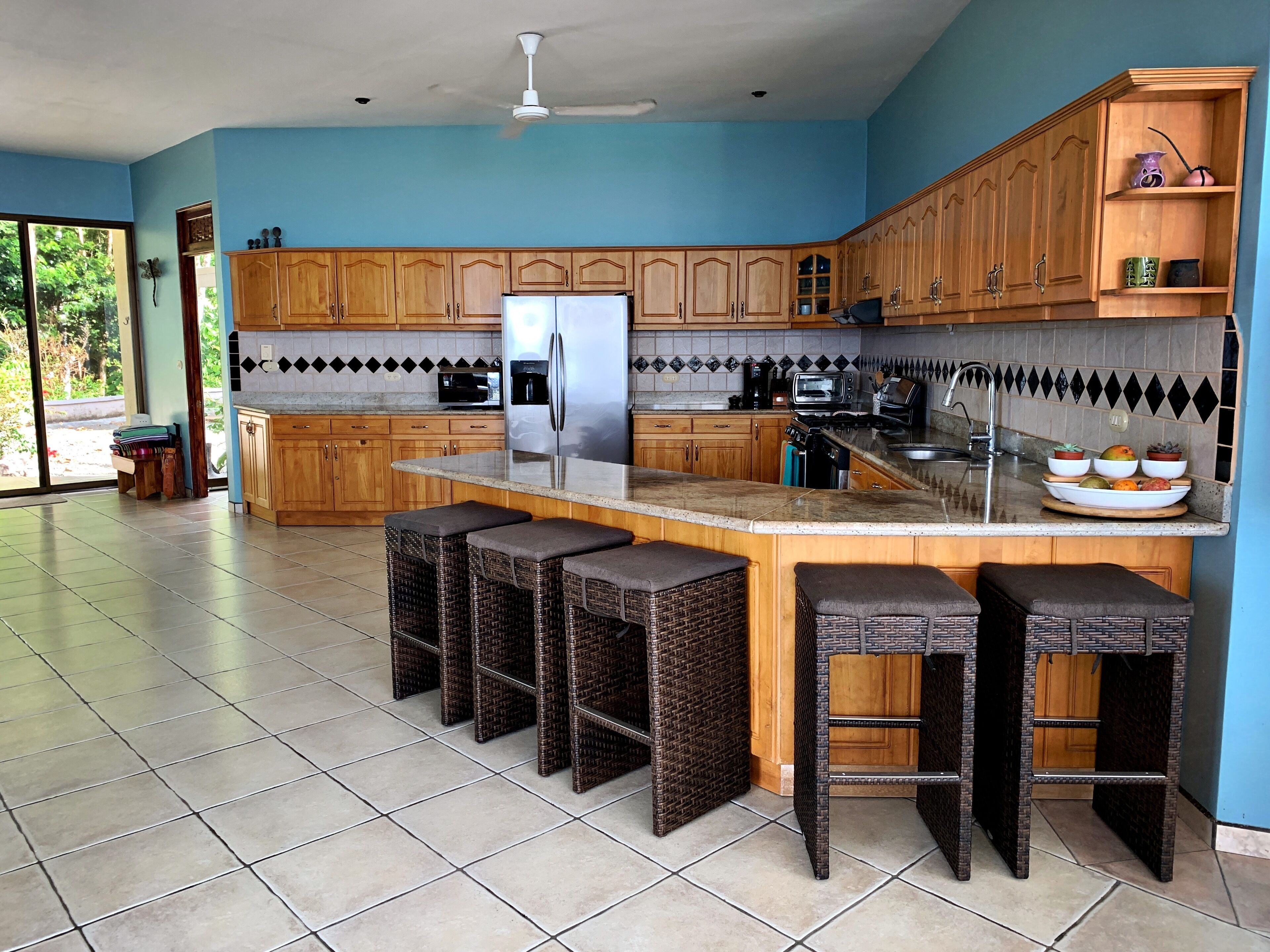Een moderne keuken met houten kastjes, een roestvrijstalen koelkast en een groot eiland met barkrukken.