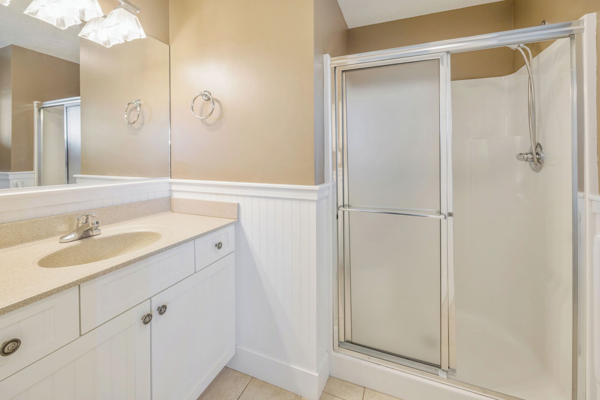 A bathroom with a double vanity, a glass shower enclosure, and a large mirror.