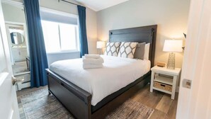 Un dormitorio con cama, mesitas de noche, un espejo y una ventana con cortinas.