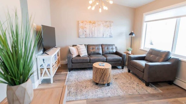 Una sala de estar moderna con un sofá, una mesa de centro y un televisor sobre un mueble.