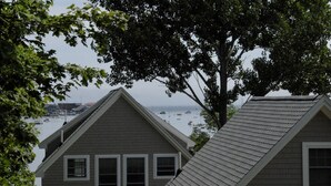 A house with a sloped roof, multiple windows, and a view of boats on the water.