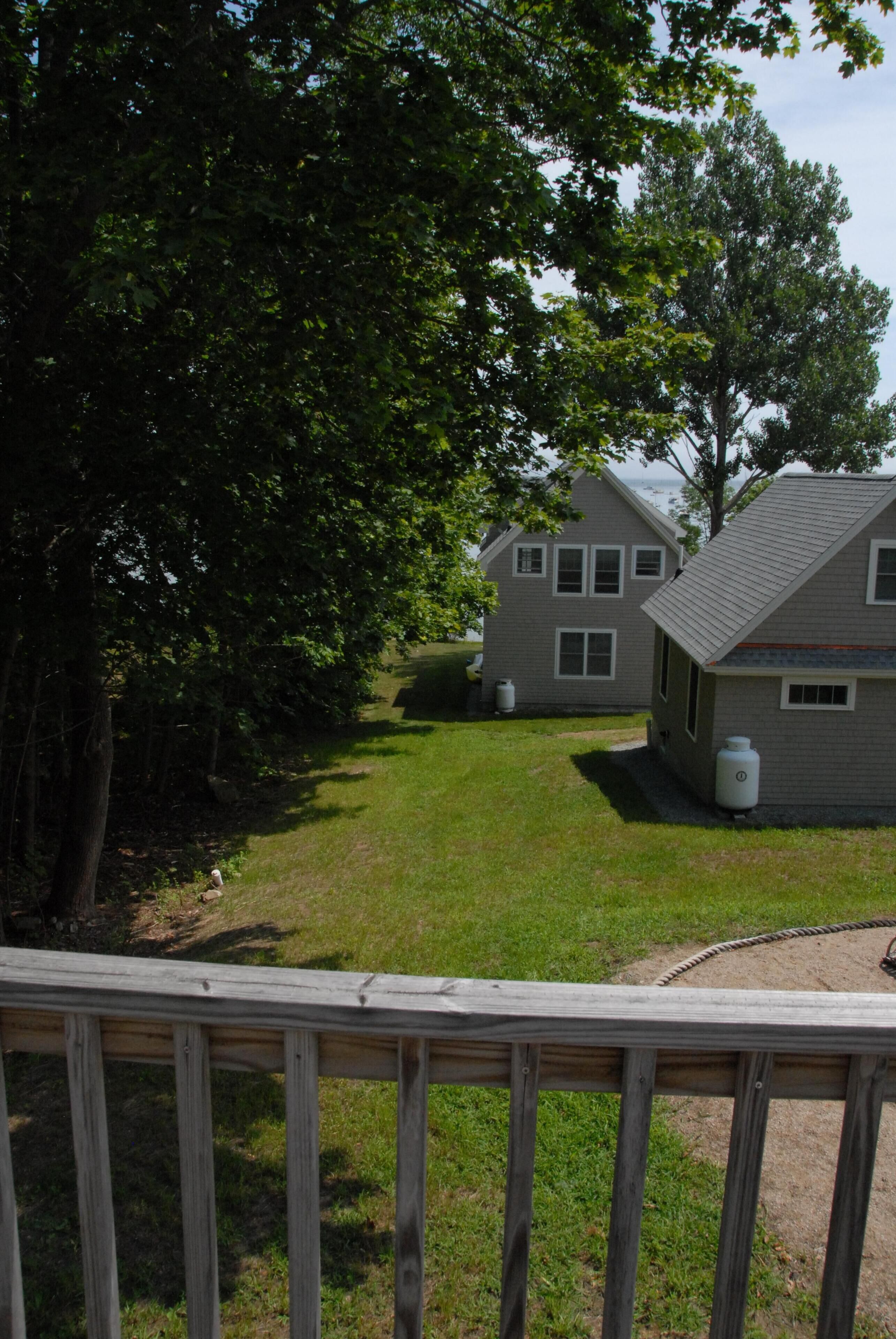 A residential area with two houses, a grassy yard, and a wooden deck.
