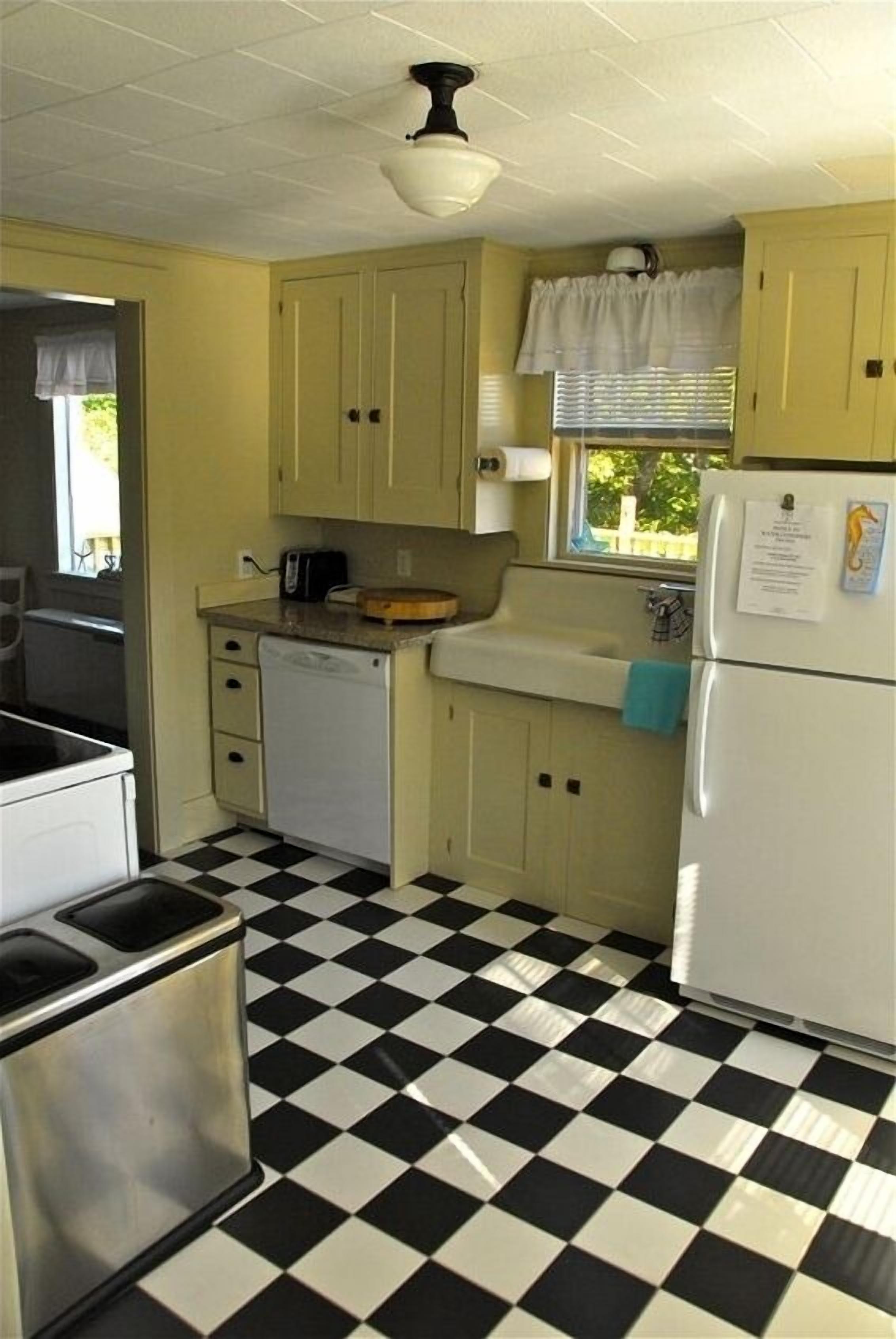 A compact kitchen with a checkered floor, a sink, a refrigerator, and basic cabinetry.
