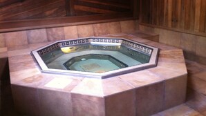 A hexagonal hot tub with a tiled surround, set against a wooden wall with a geometric pattern. - Top Rated Creekside Gem Is Steps From Free Bus To Skiing, Shopping, & Dining! (Vail)