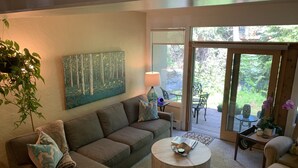 A cozy living room with a sectional sofa, a round coffee table, and a painting on the wall. - Top Rated Creekside Gem Is Steps From Free Bus To Skiing, Shopping, & Dining! (Vail)