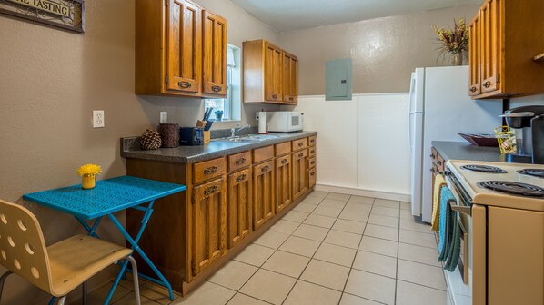 A kitchen with wooden cabinets, a blue table, a stove, and a microwave.