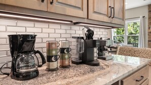 Een keuken met houten kastjes, een marmeren aanrechtblad en een koffiezetapparaat.