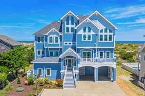A large, multi-story house with a prominent front entrance, a covered garage, and a balcony.