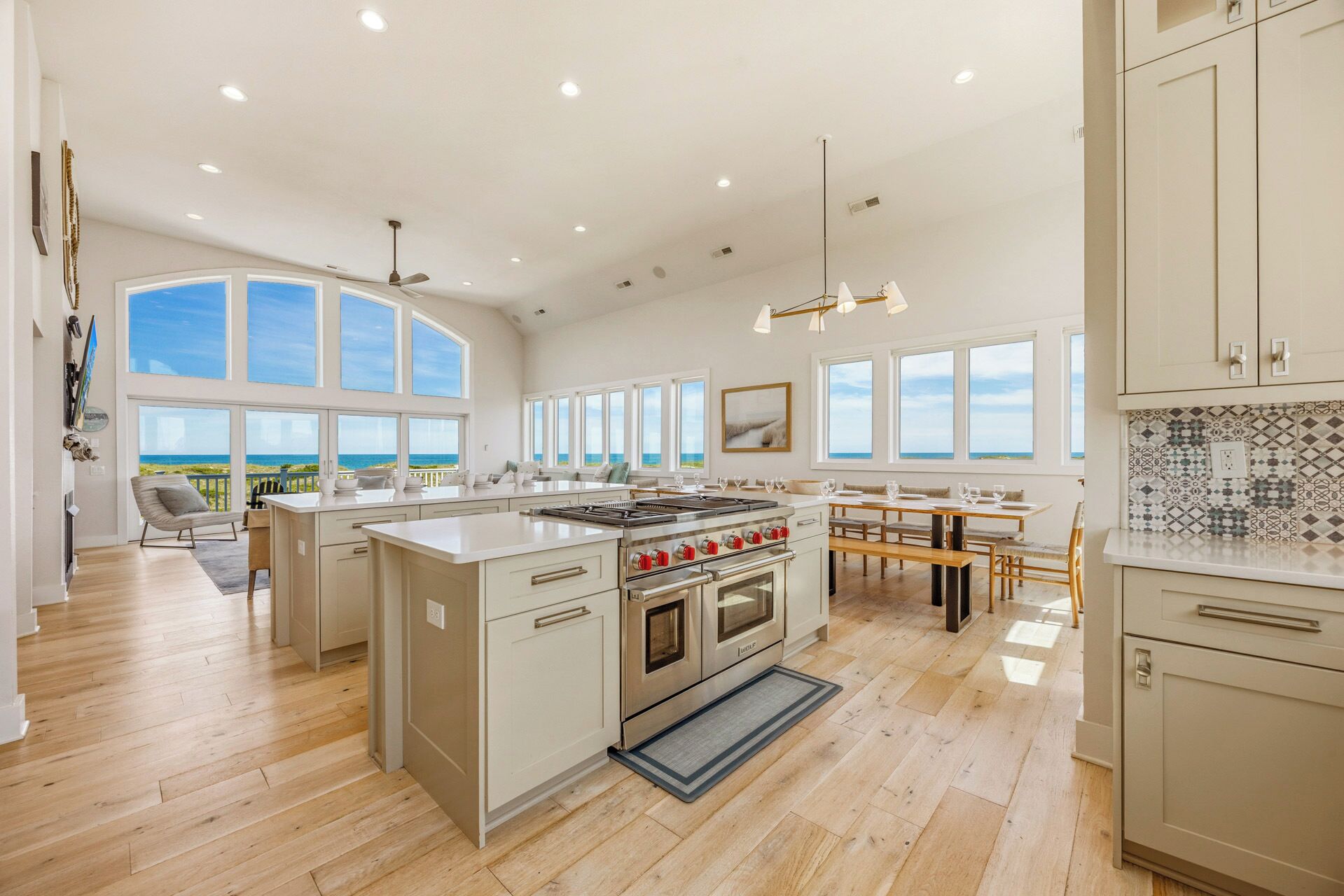 A spacious kitchen with a large island, a dining area, and a view of the ocean.