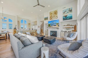 Ein geräumiges Wohnzimmer mit Kamin, ein Essbereich mit Aussicht und eine Küche mit großen Fenstern.