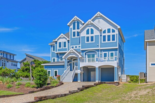 A multi-story residential building with a prominent front porch and a staircase leading to the entrance.