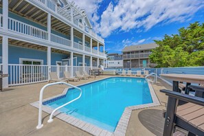 A swimming pool with a deck area, lounge chairs, and a multi-level building with balconies. - Premier Oceanfront w/ Pool, Hot Tub, Elevator, Game & Theater Rooms, Tiki Bar (Avon)