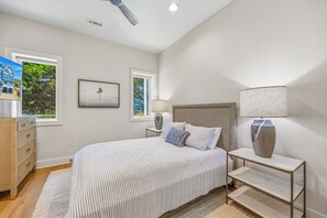 A bedroom with a bed, bedside tables, a dresser, and two windows. - Premier Oceanfront w/ Pool, Hot Tub, Elevator, Game & Theater Rooms, Tiki Bar (Avon)