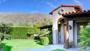 A house with a tiled roof, a well-maintained lawn, and a mountain in the background.