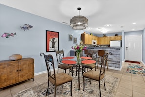 Un comedor con mesa de vidrio, sillas y un centro de mesa decorativo.