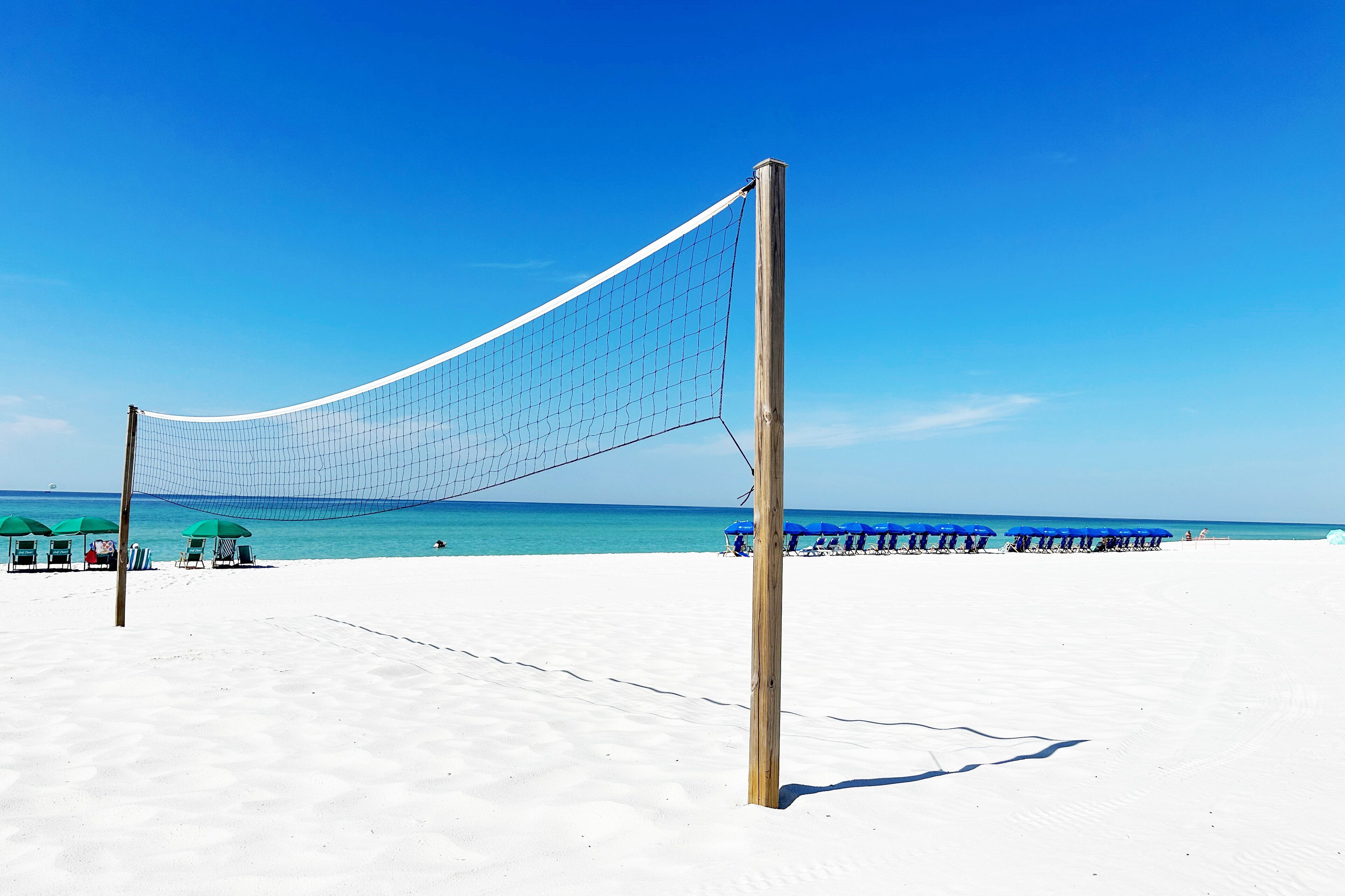 Un filet de volley-ball de plage installé sur une plage de sable, avec un ciel bleu dégagé.