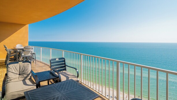 A balcony with outdoor seating, a view of the ocean, and a clear sky. - Modern 4 bedroom Condo - Phoenix Orange Beach 1701 (Orange Beach)