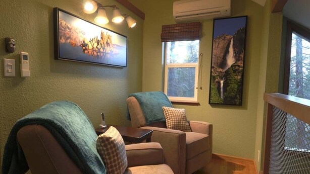 Quarto com duas poltronas de couro, uma mesa pequena e janela com vista para a montanha.