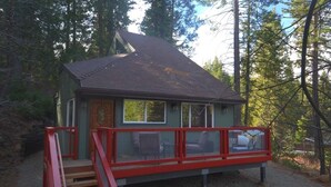 Uma pequena cabana com um deck vermelho e uma escada que leva à entrada.