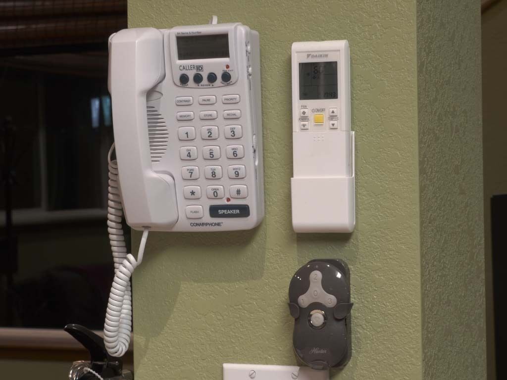 A wall-mounted telephone, a digital clock, and a doorbell.