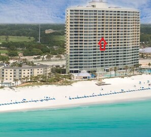 A beachfront hotel with a large building, a sandy beach, and clear turquoise waters.