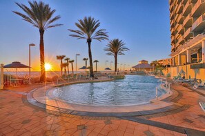 A swimming pool area with palm trees, sun loungers, and a building in the background. - Breathtaking views - Beautifully decorated/3 Bedroom - 12th Floor (Panama City Beach)