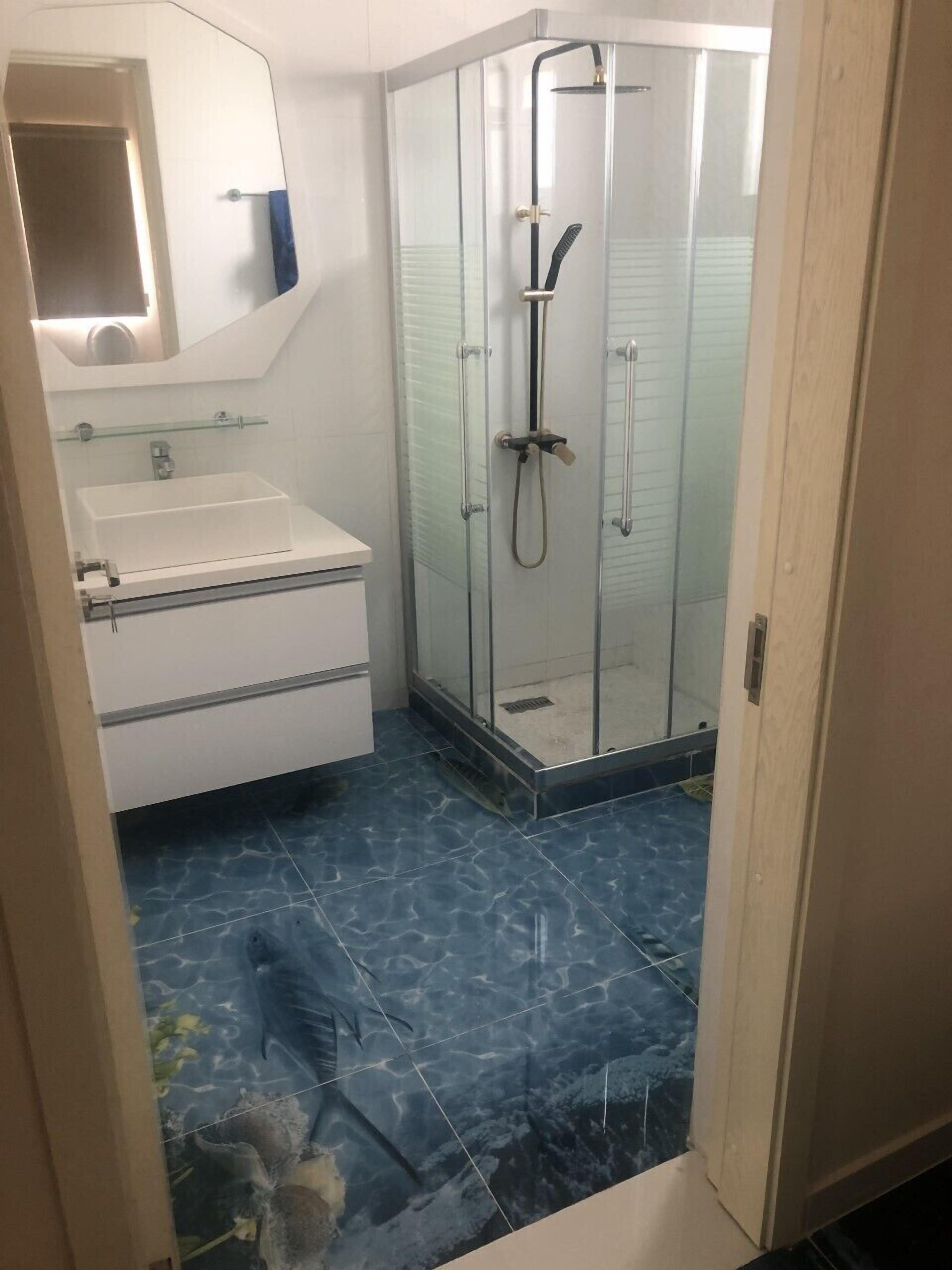Een badkamer met een douche met glazen wanden, een wit wastafelmeubel en een spiegel boven de wastafel.