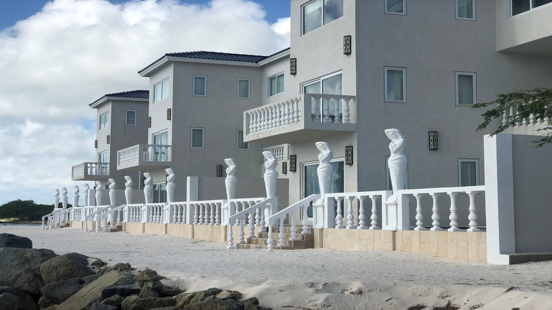 Eine Reihe moderner Gebäude mit Balkonen und einem weißen Zaun, der Statuen zeigt.