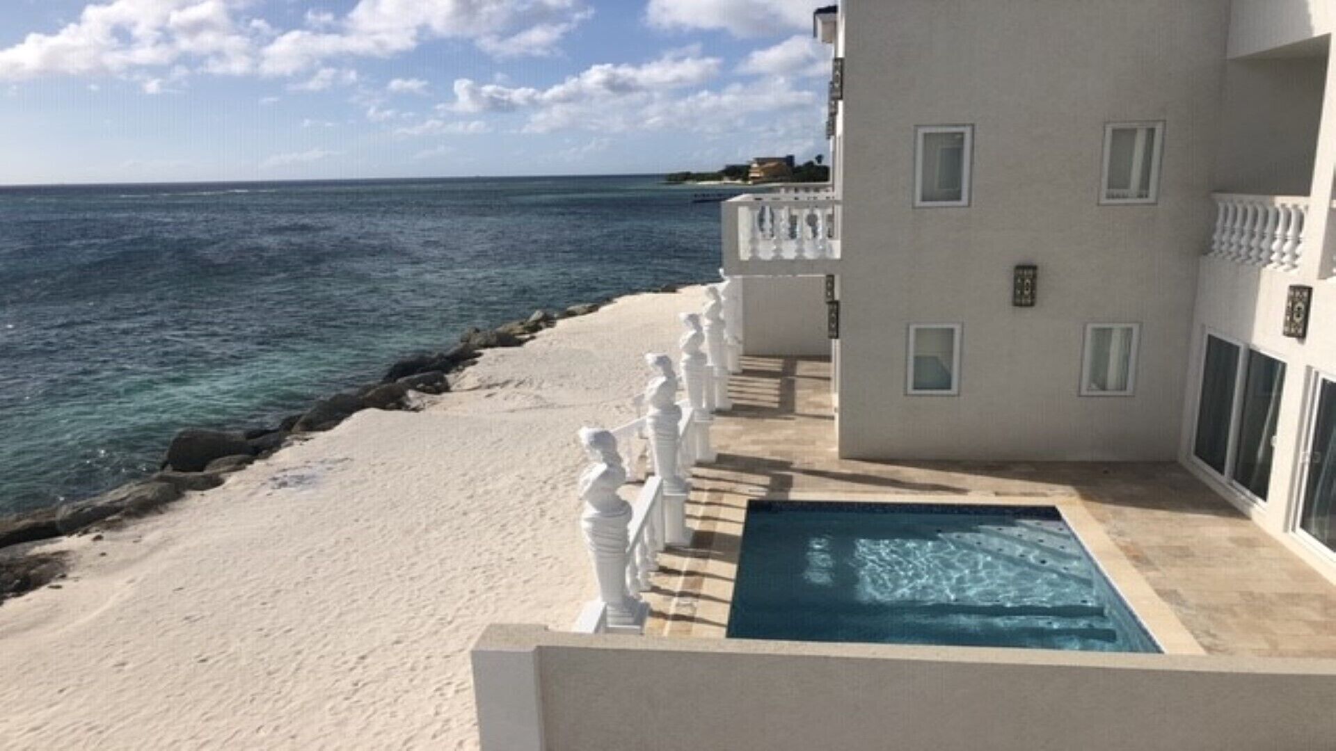 A beachfront property with a swimming pool, a sandy beach, and a view of the ocean.
