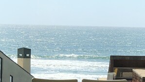 A view of the ocean from a balcony with a building in the foreground. - Sweeping ocean views! Perfect for families, steps to sand, ping pong, Pickleball (Watsonville)